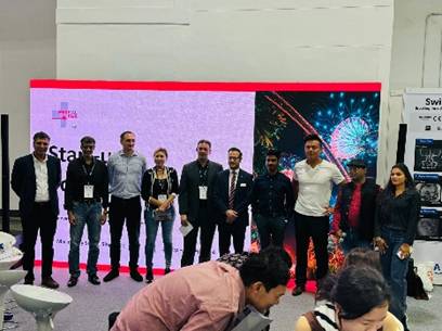 A group of people standing in front of a large screen

Description automatically generated
